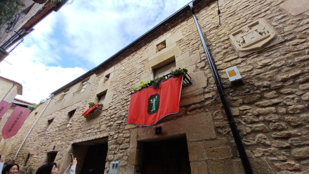 スペイン・バルゴタで、建物の間に祭りの旗が飾られた石造りの路地。