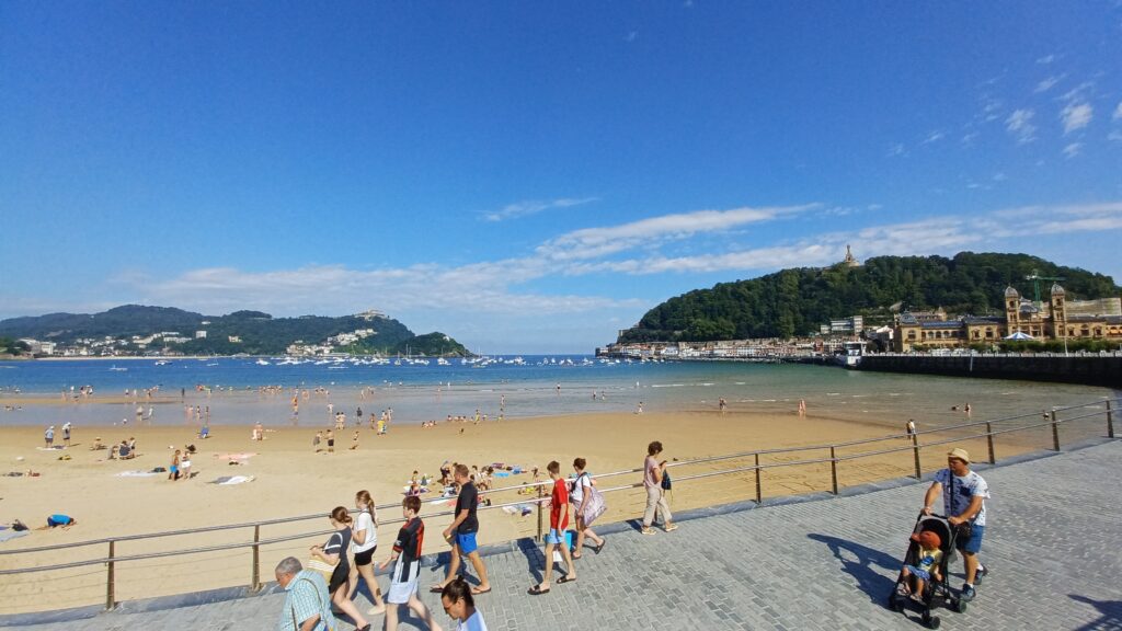 人々が歩くコンチャ海岸の砂浜と山を背景にした景色