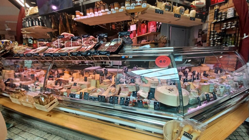 チーズや生ハムが並ぶ食料品店のショーケース